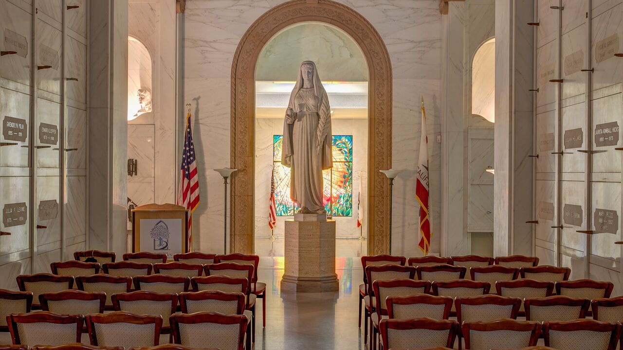 Old Chapel of Woodlawn Cemetery's Mausoleum with rows of chairs in front of large statue and stained glass windows